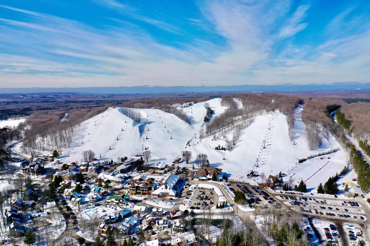 Aerial view of snow-covered ski slopes and resort buildings on a clear day.