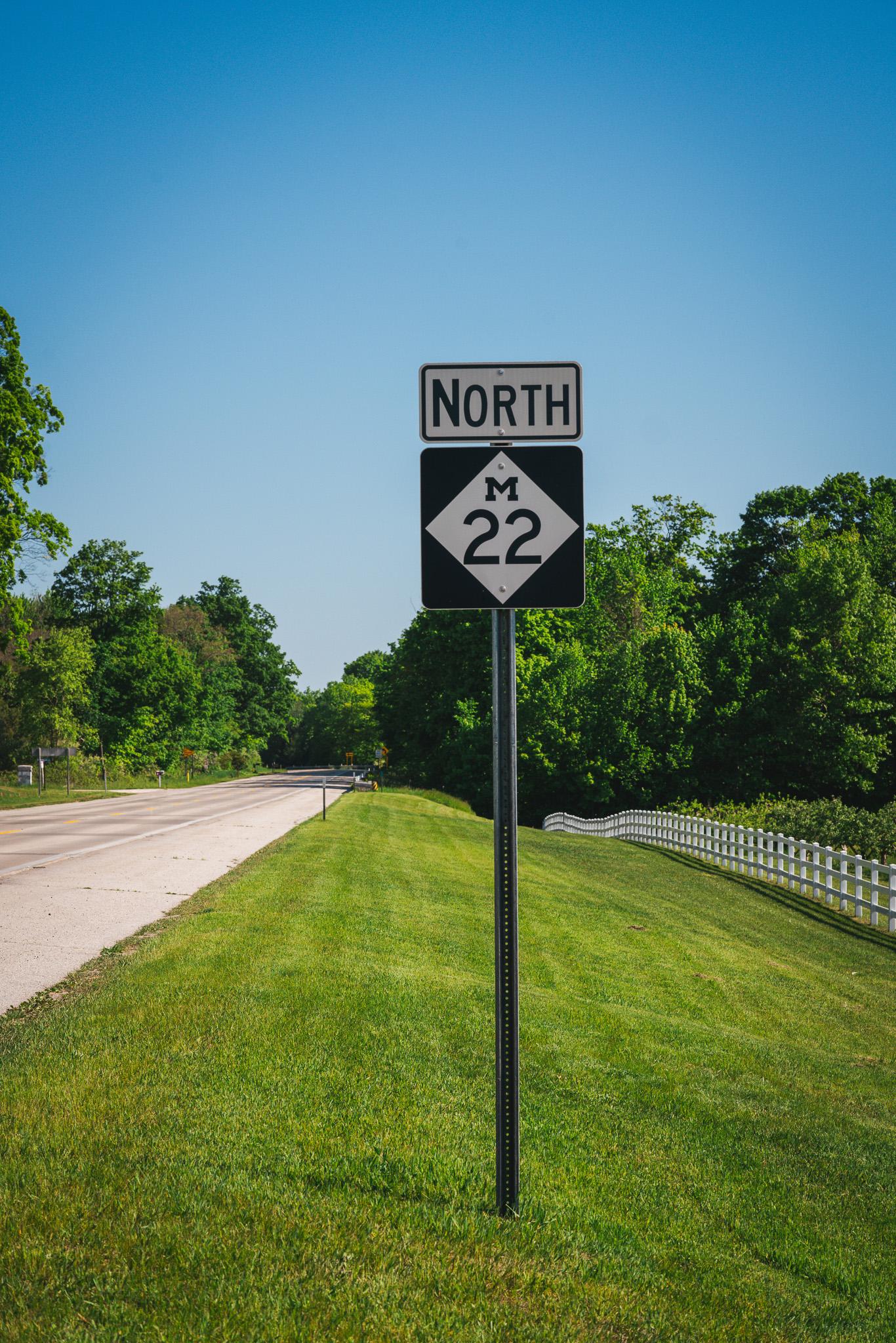 Road sign for North Route 22, beside a tree-lined rural road.