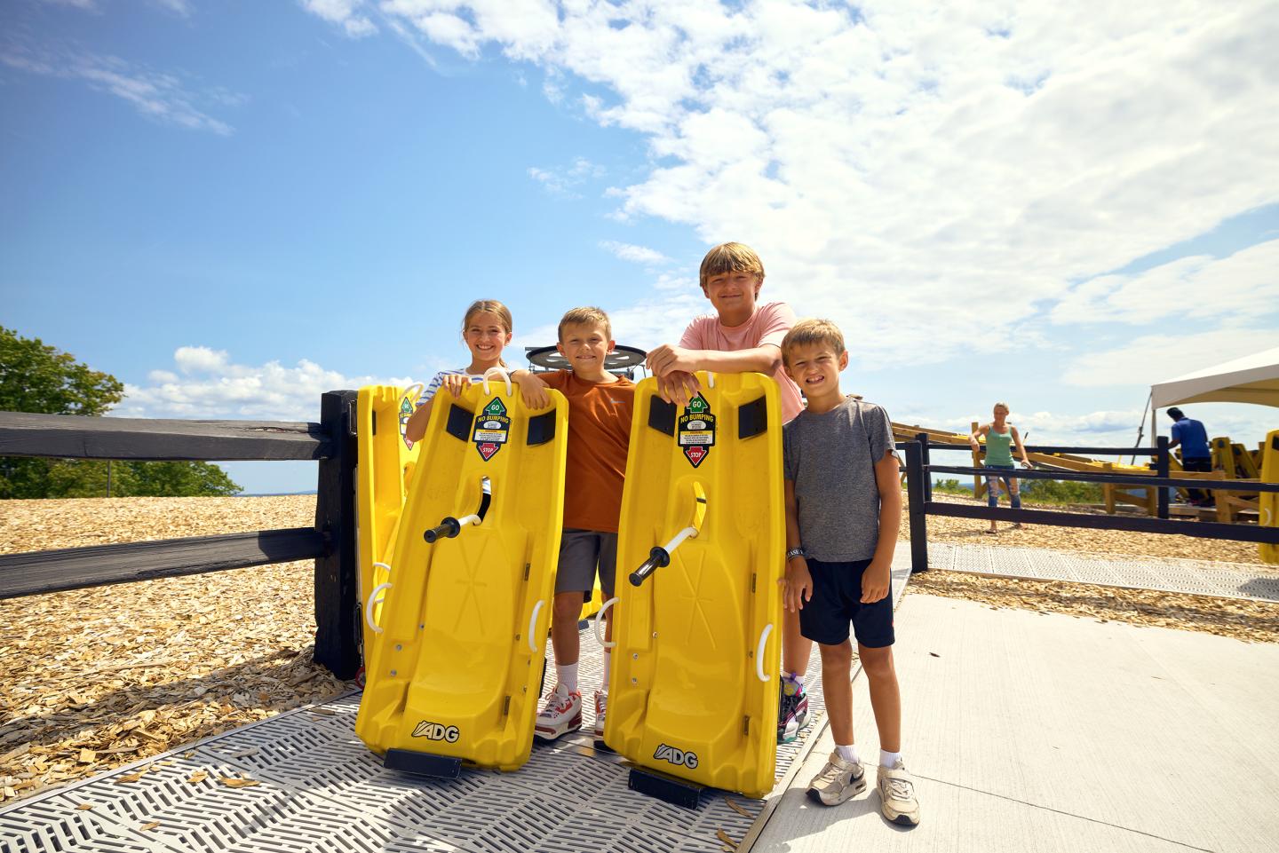 Four boys stand with yellow beach rental boards on a sunny day.