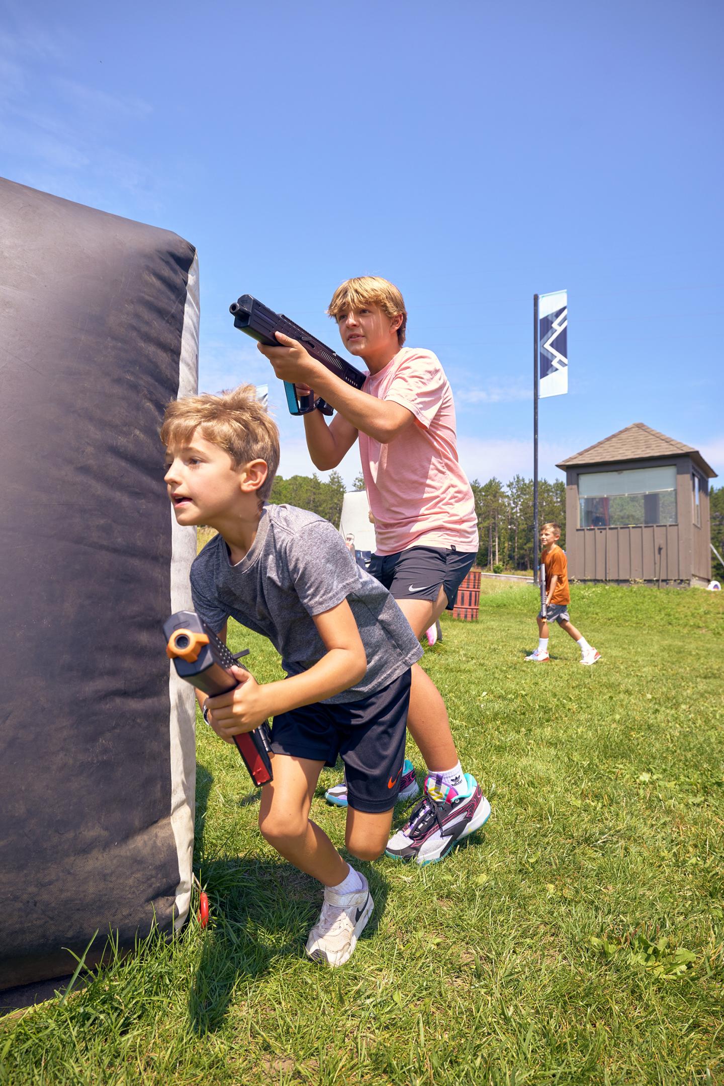Boys playing with water guns outside on a sunny day.