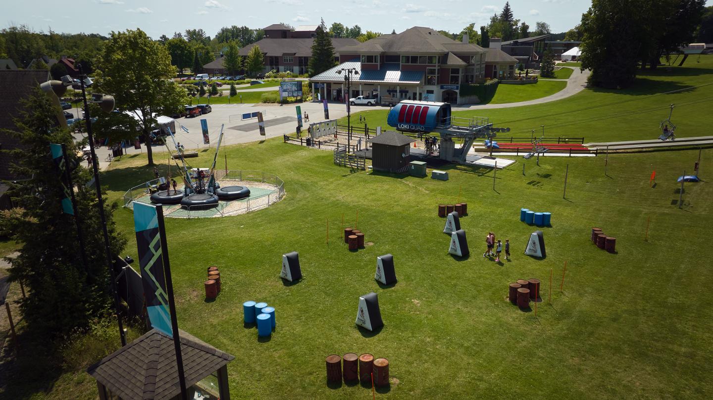 Outdoor paintball field with inflatable barricades and nearby buildings. Sunny day.