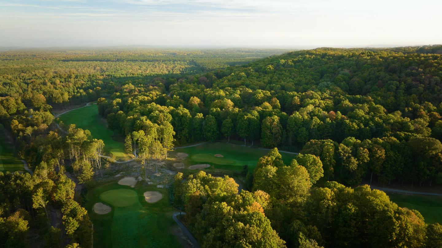 Aerial view of a lush green forested landscape with a golf course.