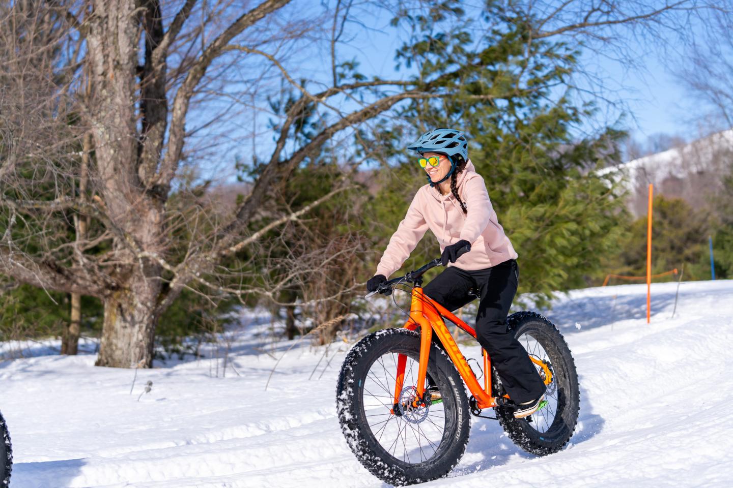 Person riding a fat bike on snow, surrounded by trees.