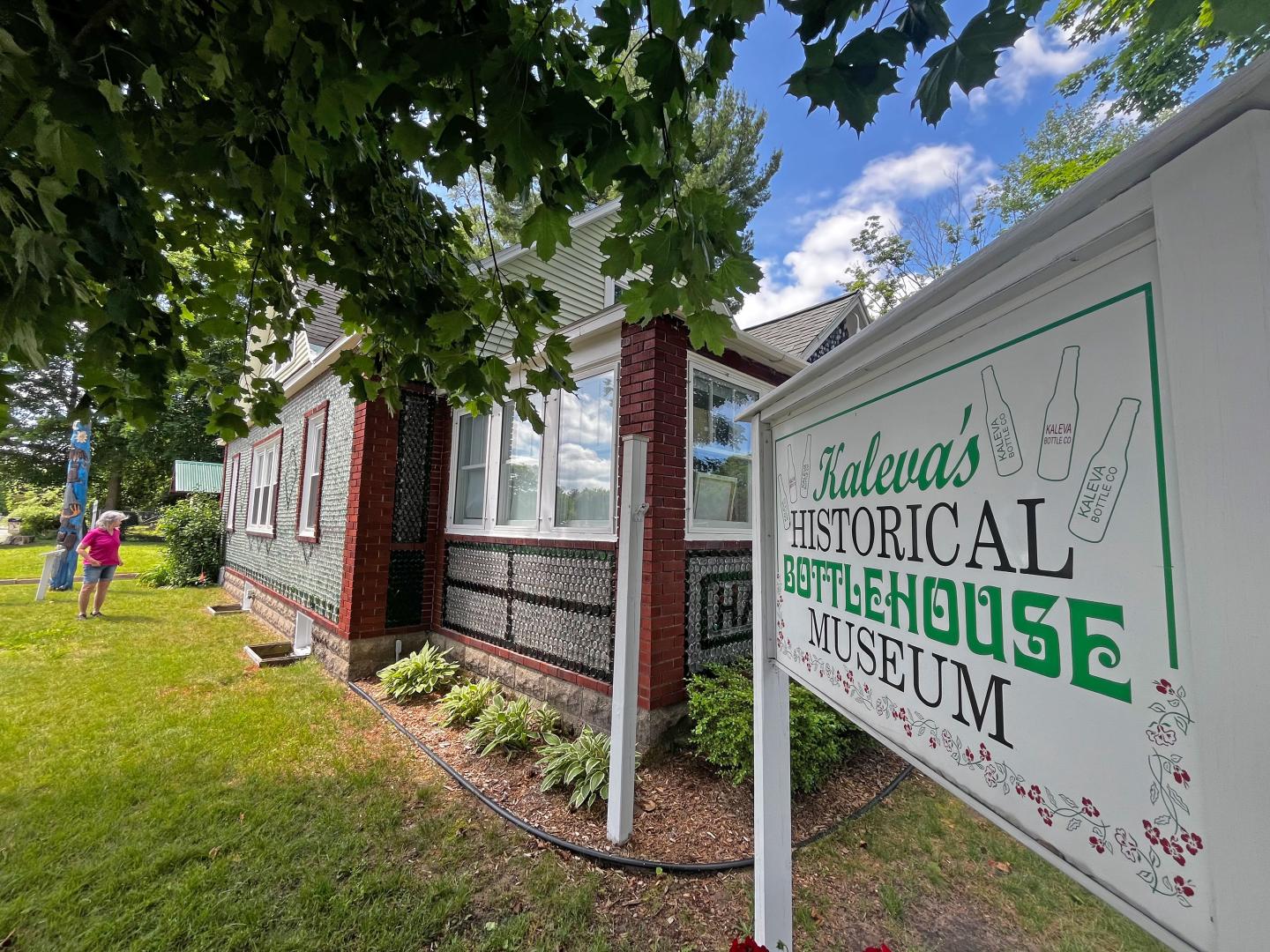Historical museum sign in front of a red-brick building on a sunny day.