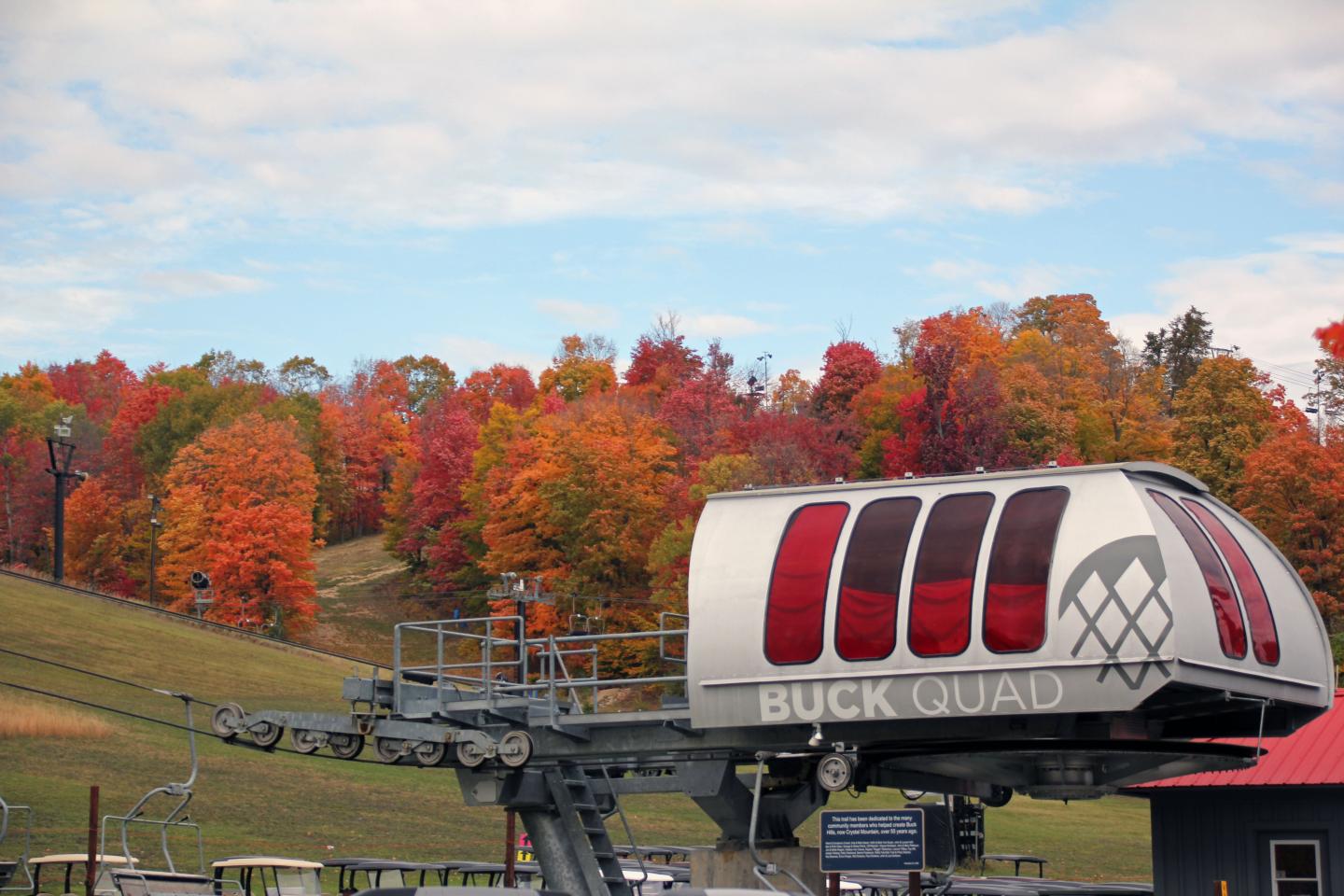 A ski lift with red windows, surrounded by vibrant autumn foliage.