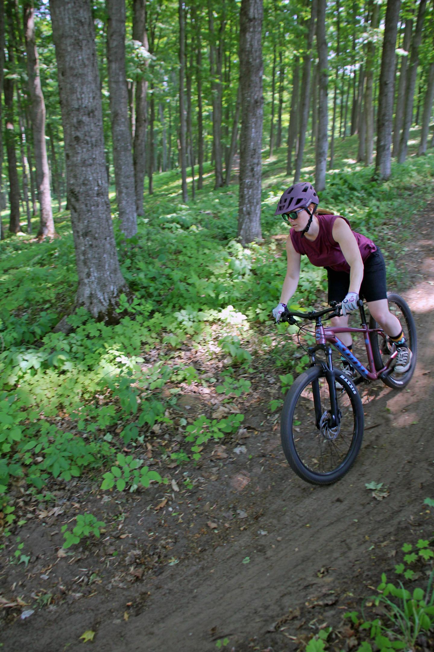 Cyclist in helmet rides through a lush, green forest trail.