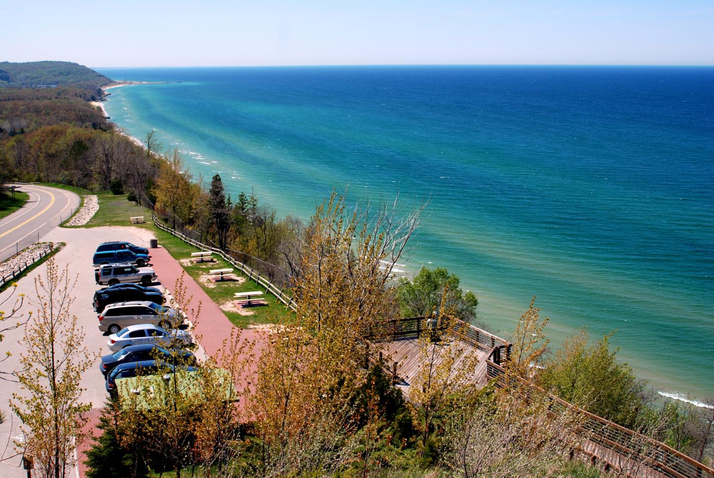 Overlooking a coastal road and parked cars by a blue-green sea.
