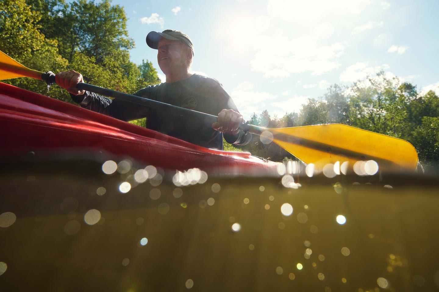 Kayaker paddling on a sunny day, water droplets in foreground.