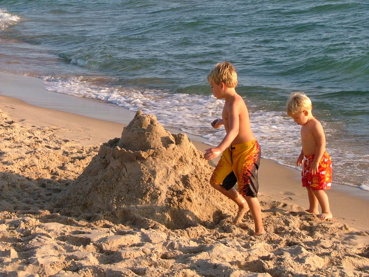 Two children building a sandcastle by the lake.