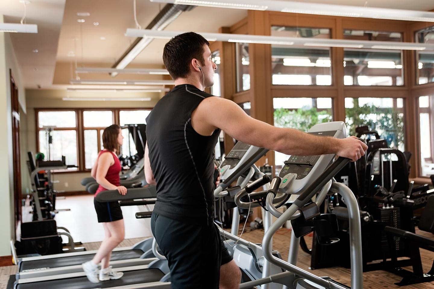 Treadmill workout in a bright gym setting with two people exercising.