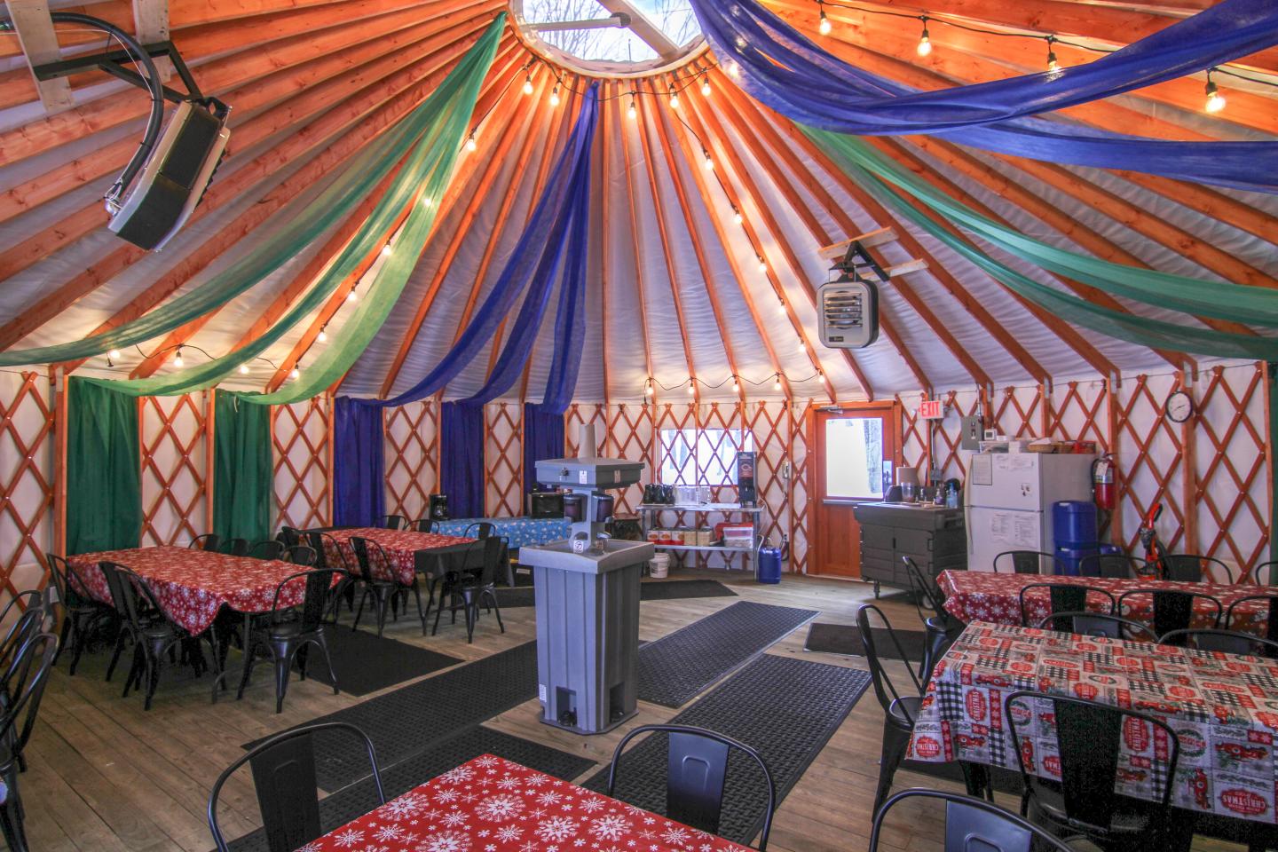 Colorful yurt interior with draped fabric ceiling, tables, and chairs.