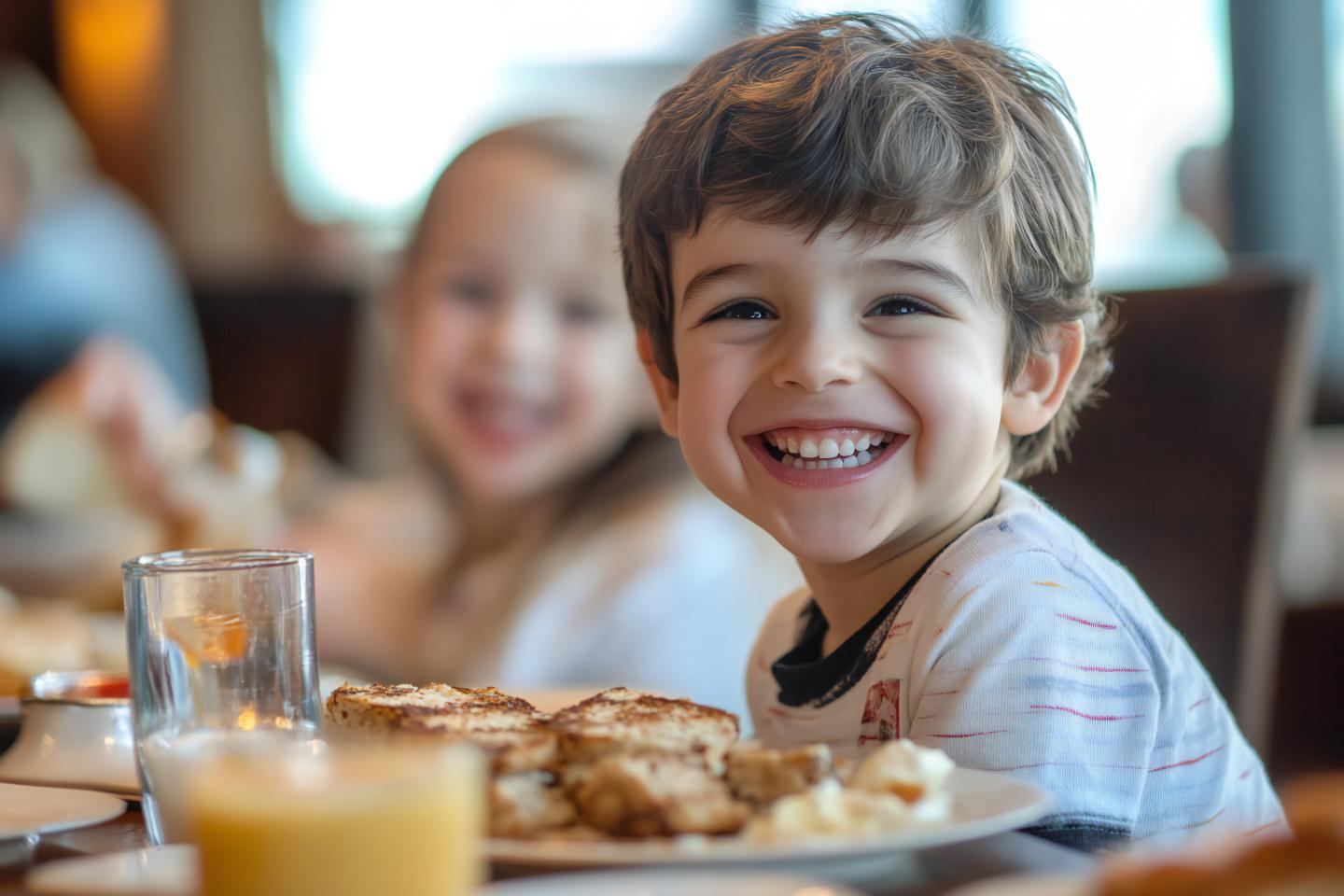 Smiling child at a table with breakfast foods.