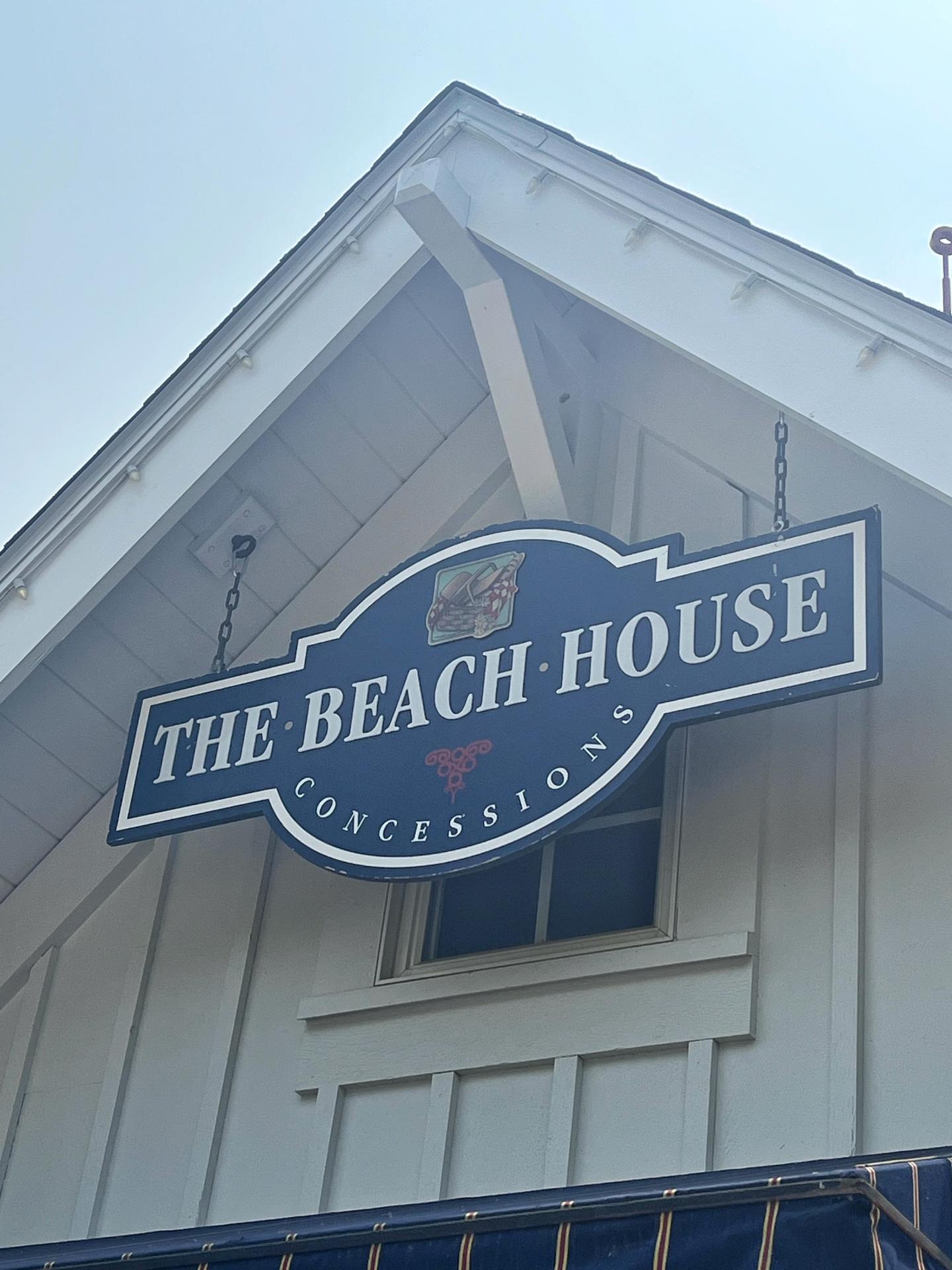 Blue sign reading "The Beach House Concessions" on a white building.