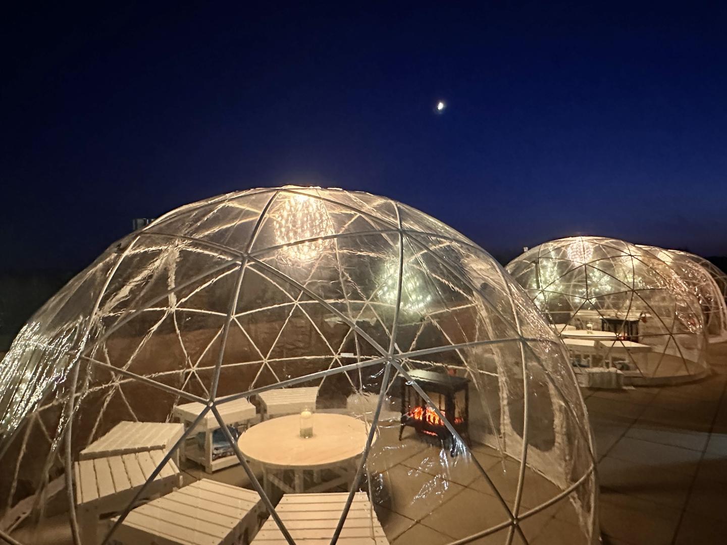 Glowing igloo domes on a rooftop under a dark sky with a crescent moon.