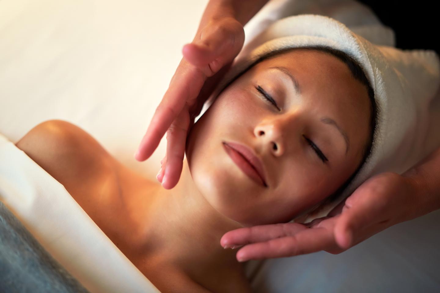 Woman receiving a relaxing facial massage with eyes closed.
