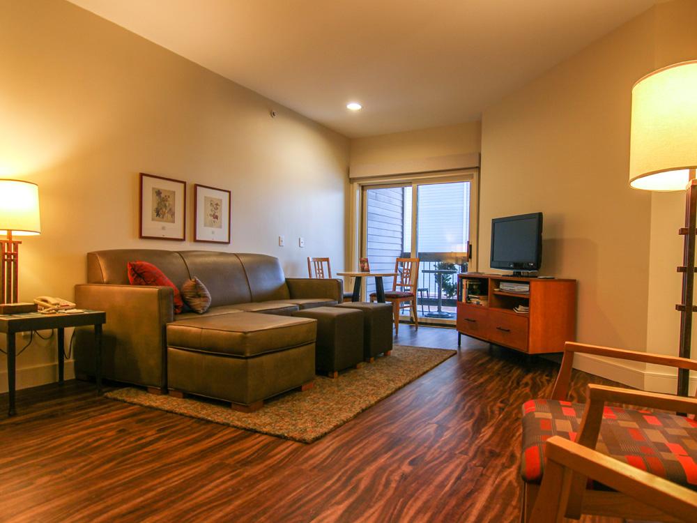 Cozy living room with a brown sofa, TV, and warm lighting.