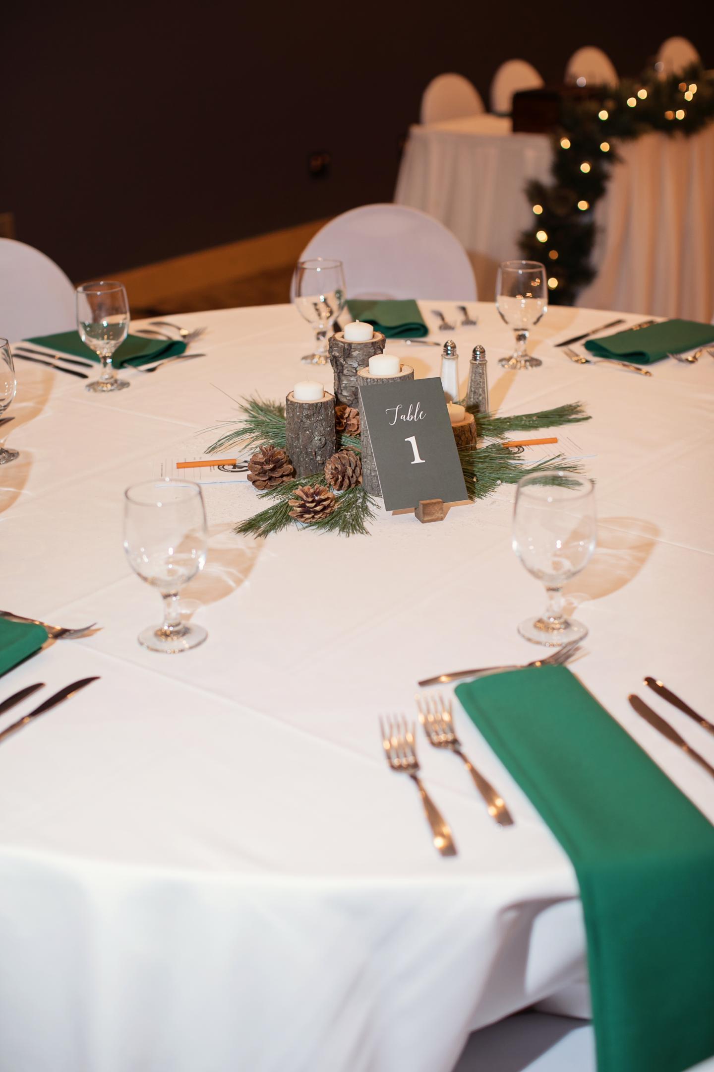 Round banquet table with green napkins and pinecone centerpiece.