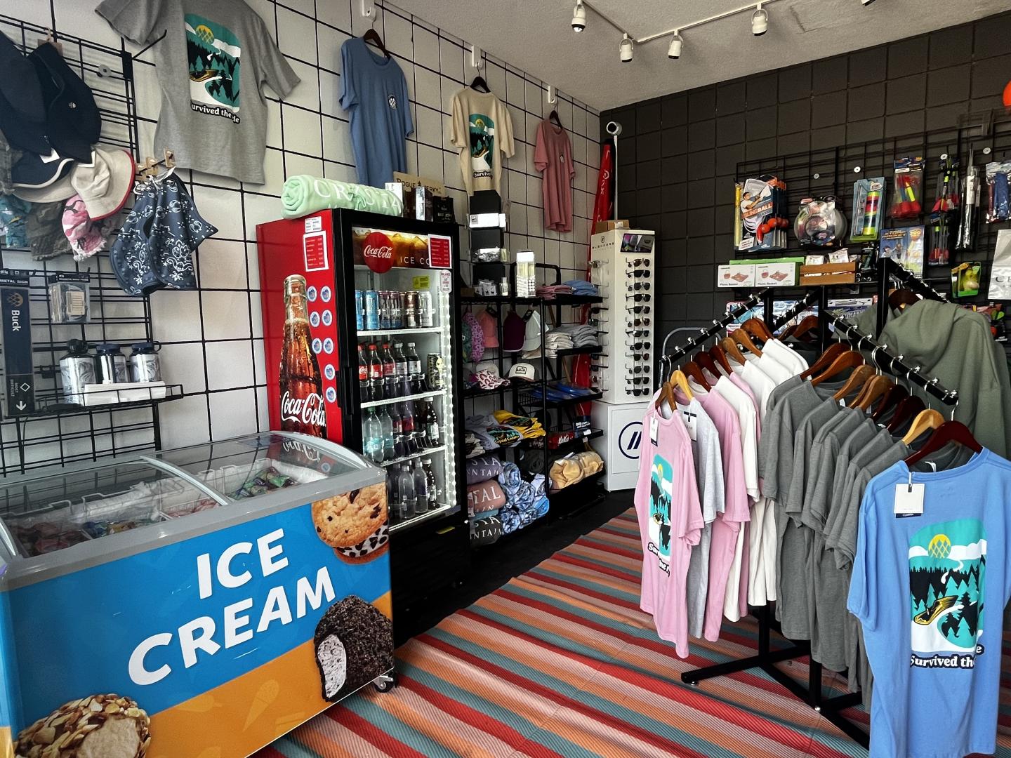 Clothing and ice cream shop with colorful shirts and a freezer.
