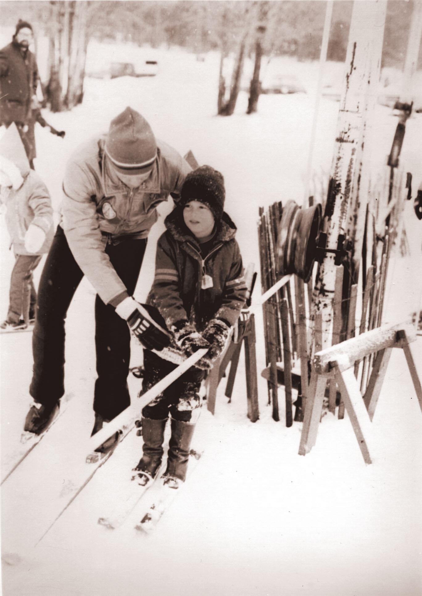 Child learning to ski with help.