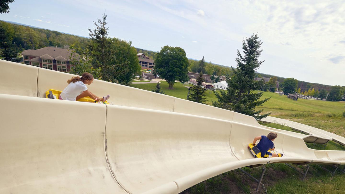 Two kids sliding down the Alpine Slide at Crystal Mountain