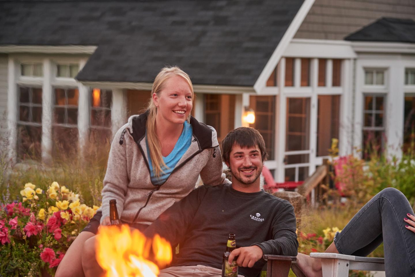 Couple sitting by a fire pit, smiling near the Bungalows.