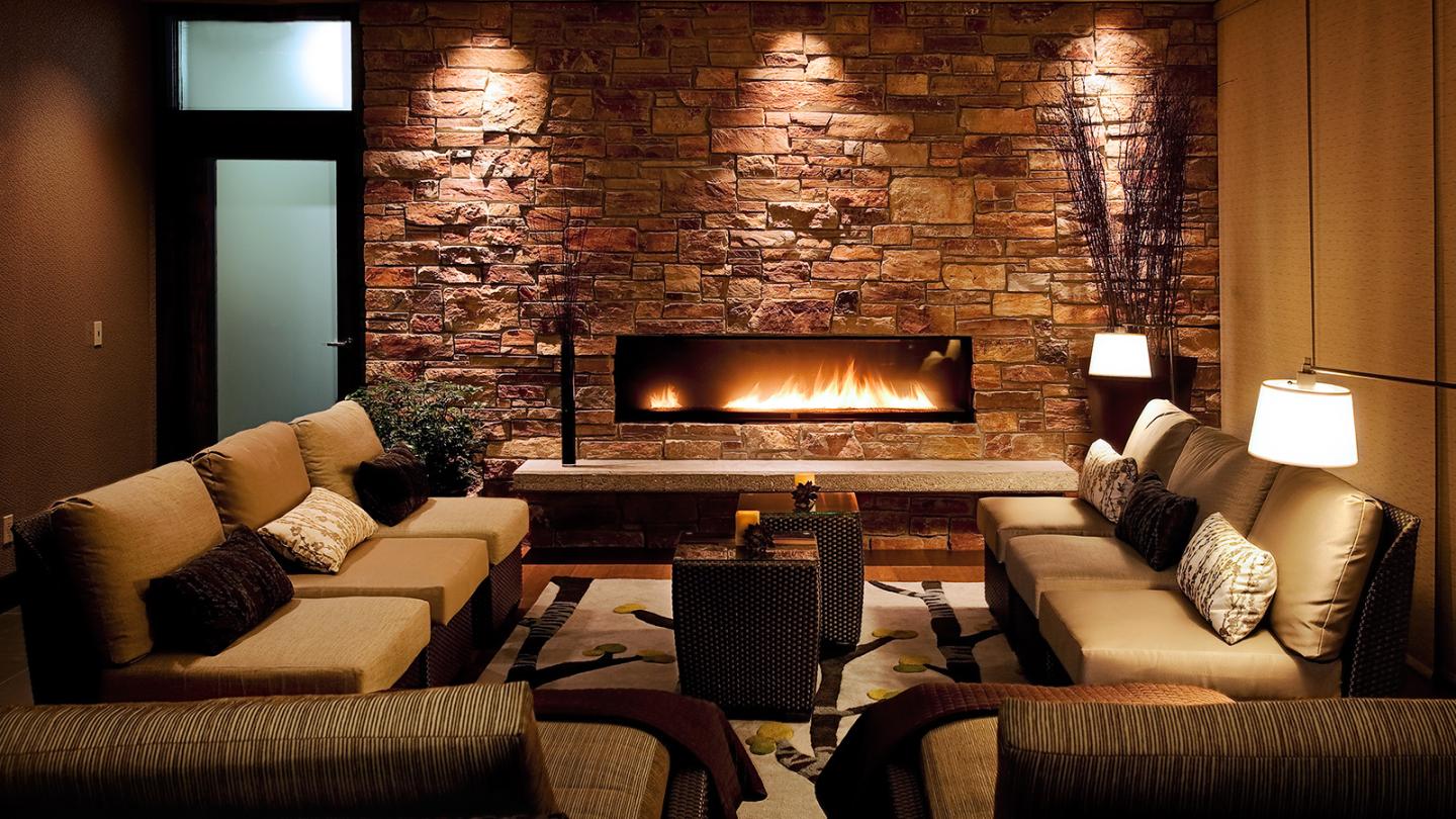 Cozy living room with sofas, brick wall, and modern fireplace.