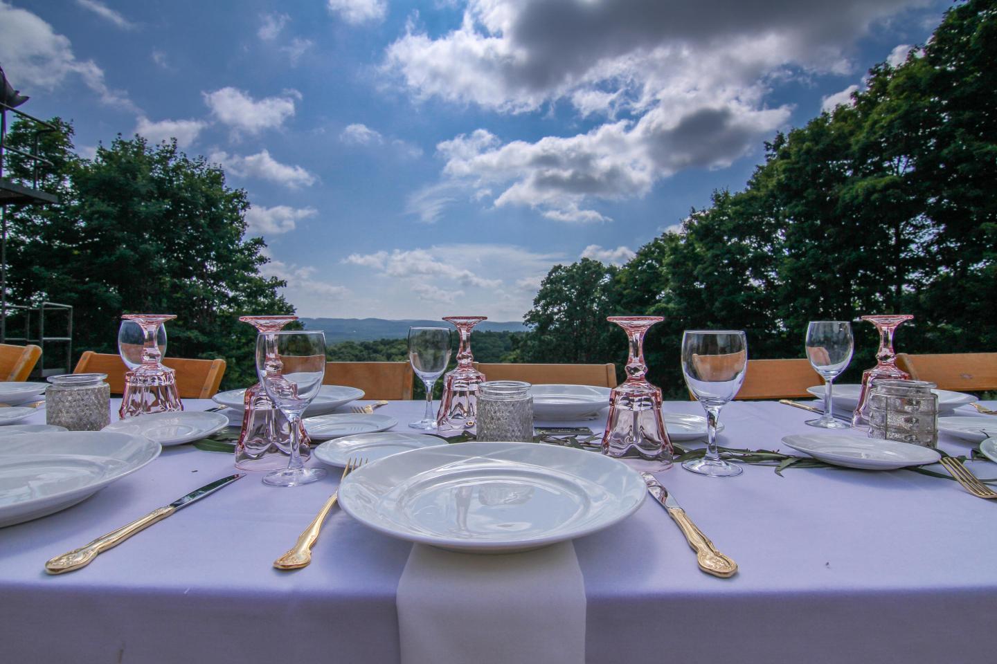 Elegant outdoor table setting under a partly cloudy sky.