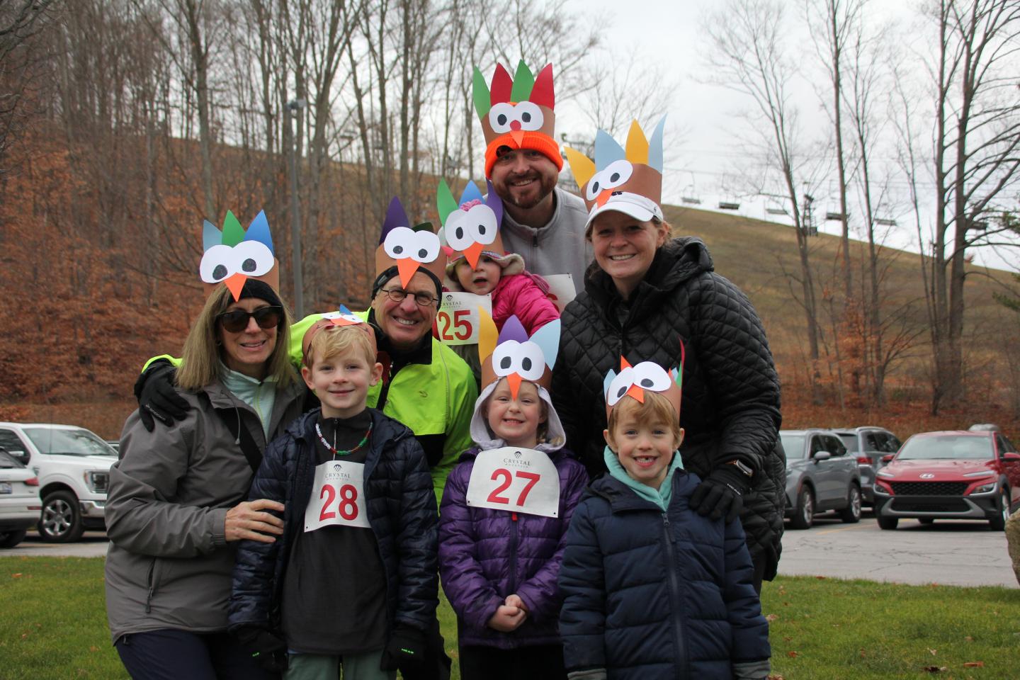 Group wearing turkey hats outdoors, smiling on a cloudy day.
