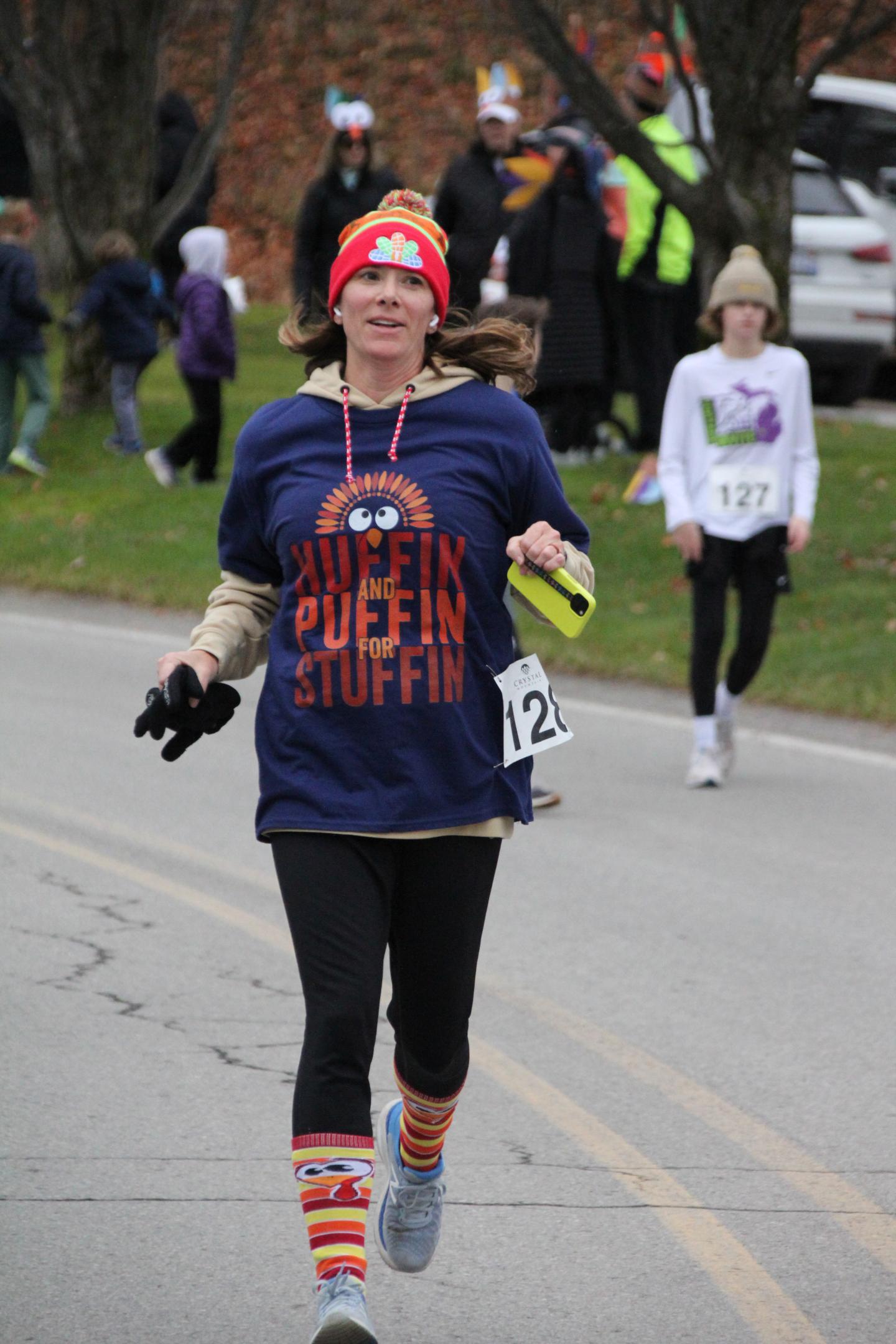 Runner on a road in fall clothing, wearing a red hat and a blue shirt.