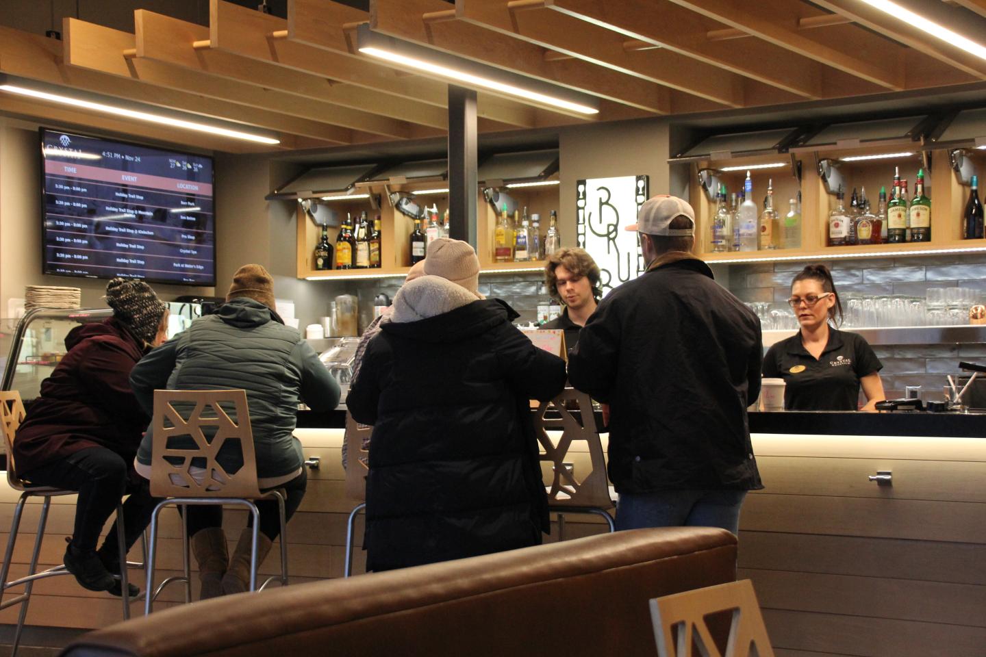 Cozy cafe scene with people sitting at a bar, chatting with staff.