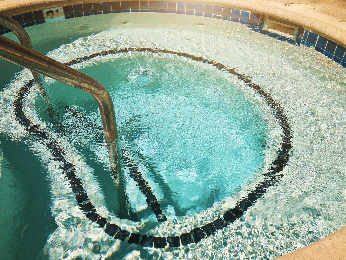 Bubbling circular hot tub with metal handrails.