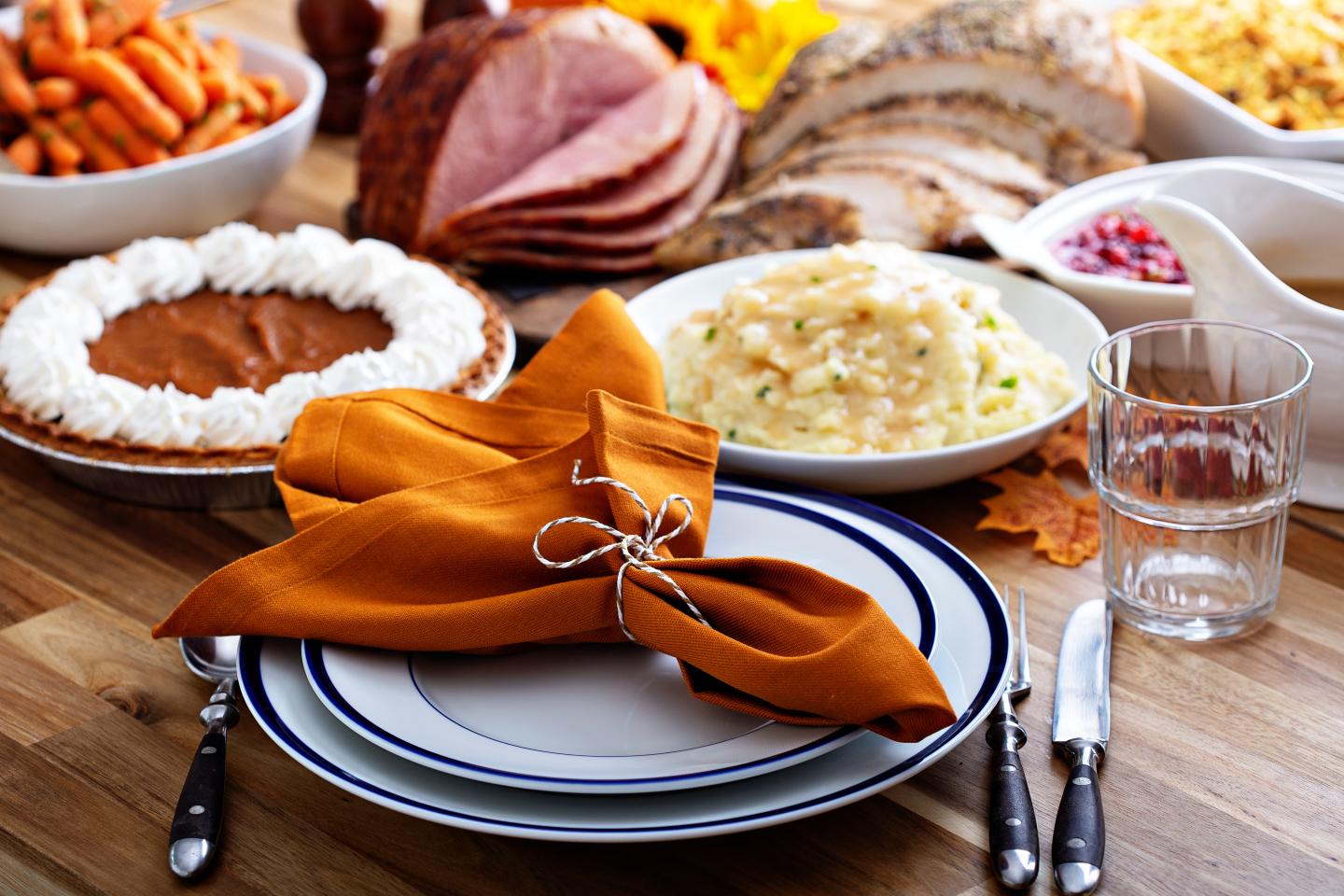 Thanksgiving meal on a table, featuring pie, turkey, and mashed potatoes.