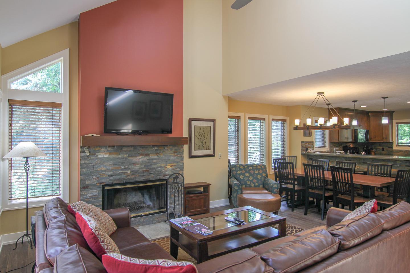 Spacious living room with brown sofas and a wall-mounted TV.
