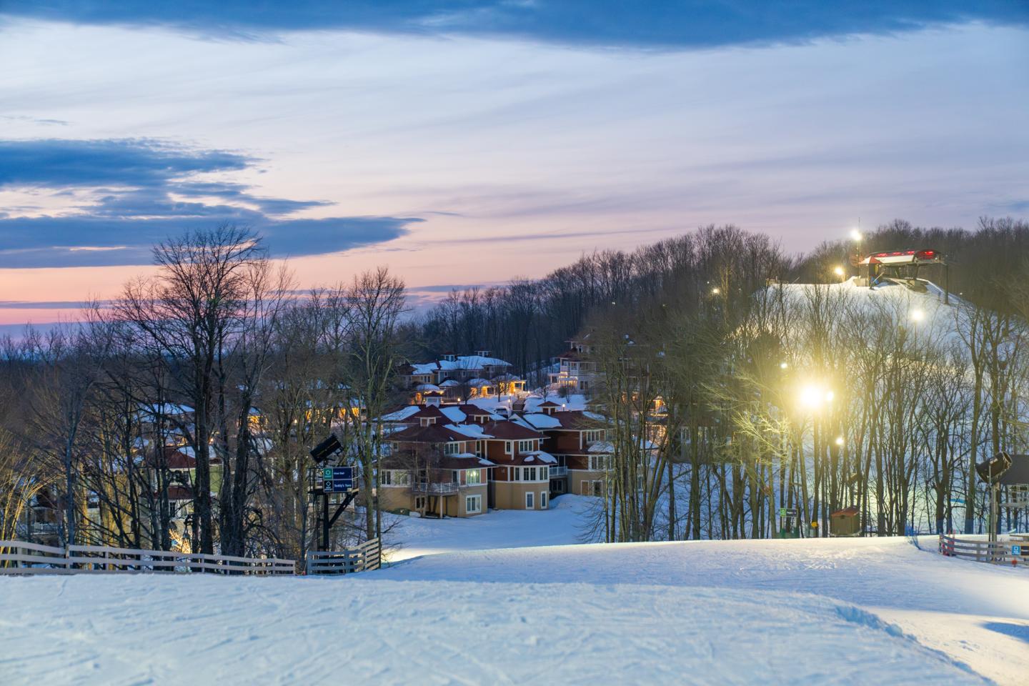 Snowy ski resort at twilight with MountainTop townhomes and slopes.