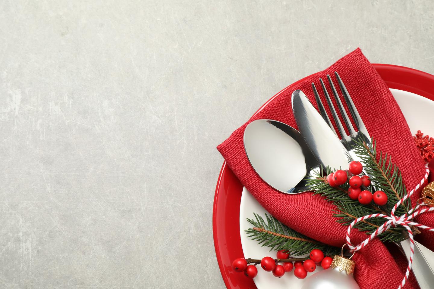 Holiday table setting with red napkin, silverware, and festive decorations.