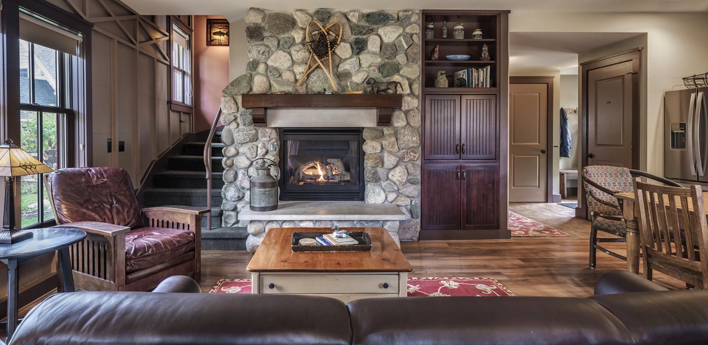 Cozy living room with stone fireplace, wooden furniture, and rustic decor.