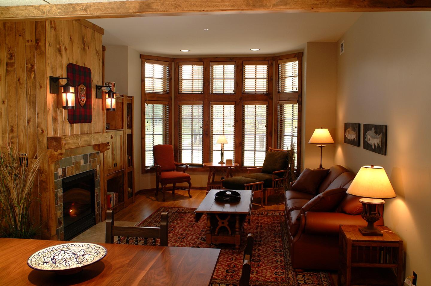 Cozy living room with a fireplace, leather sofa, and large windows.