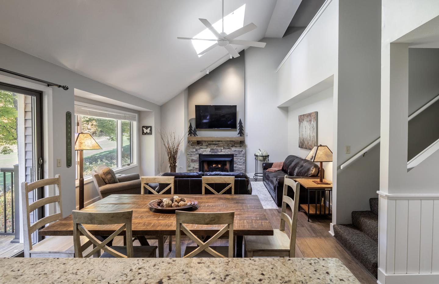 Open-concept living room with dining area, cozy couches, and a fireplace.