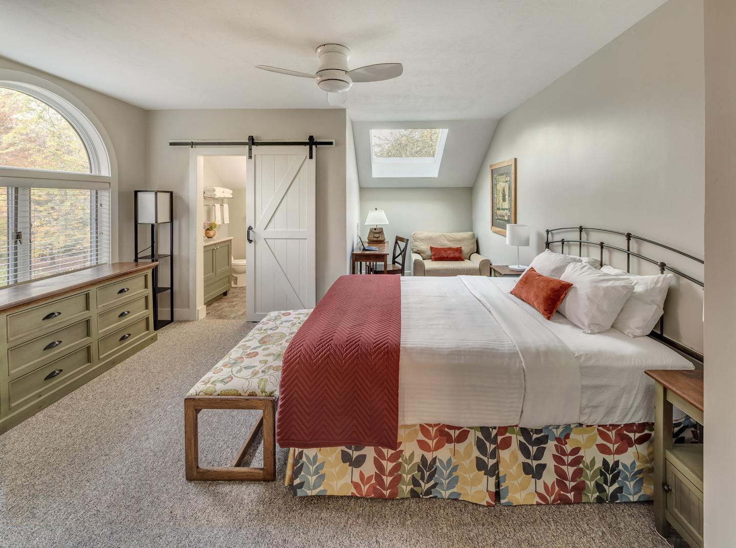 Spacious bedroom with large bed, wooden furniture, and skylight.