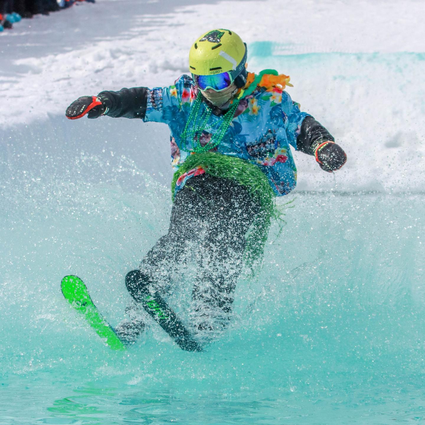 Skier in bright gear splashing through icy water.