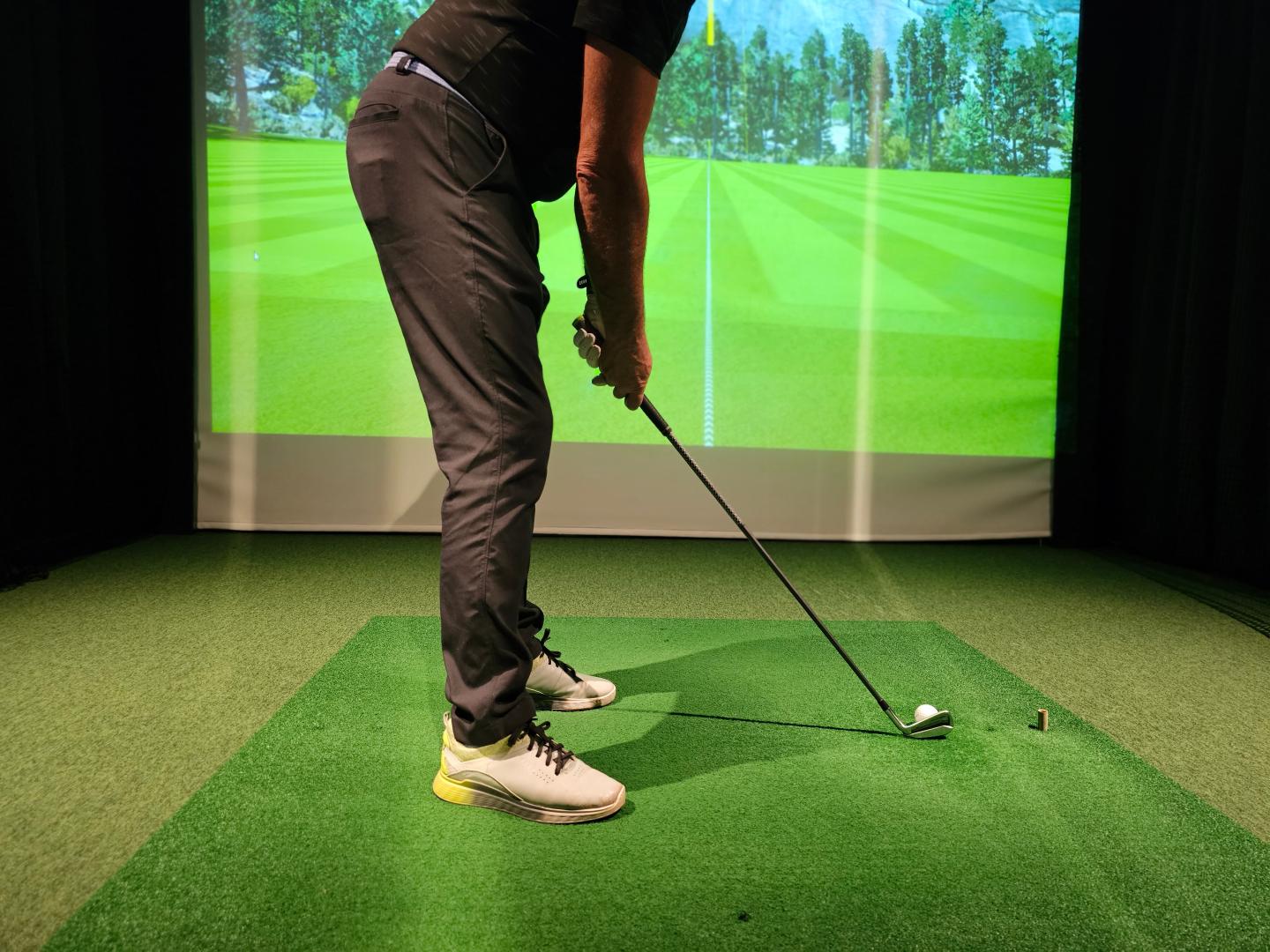 Golfer preparing to tee off on a golf simulator.