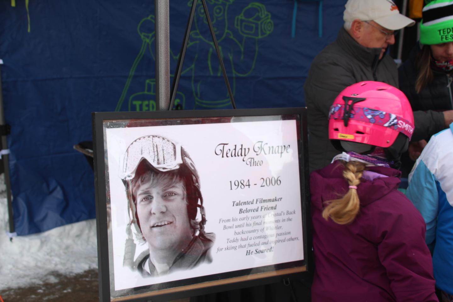 Memorial plaque with people in winter gear nearby.