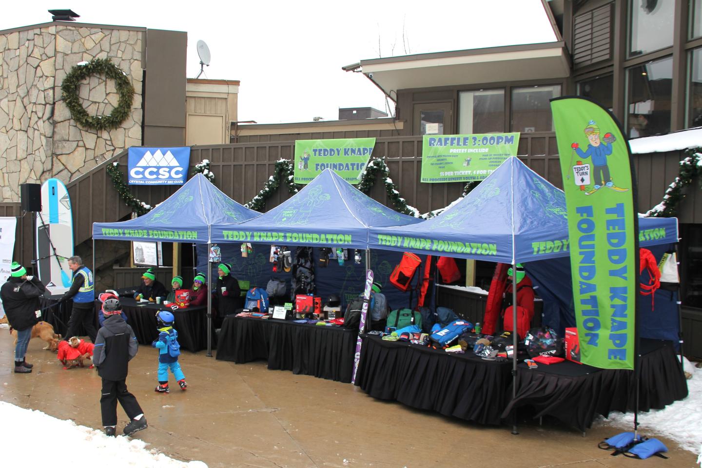 Blue tents at Teddy Fest, people in winter clothing, snow on the ground.