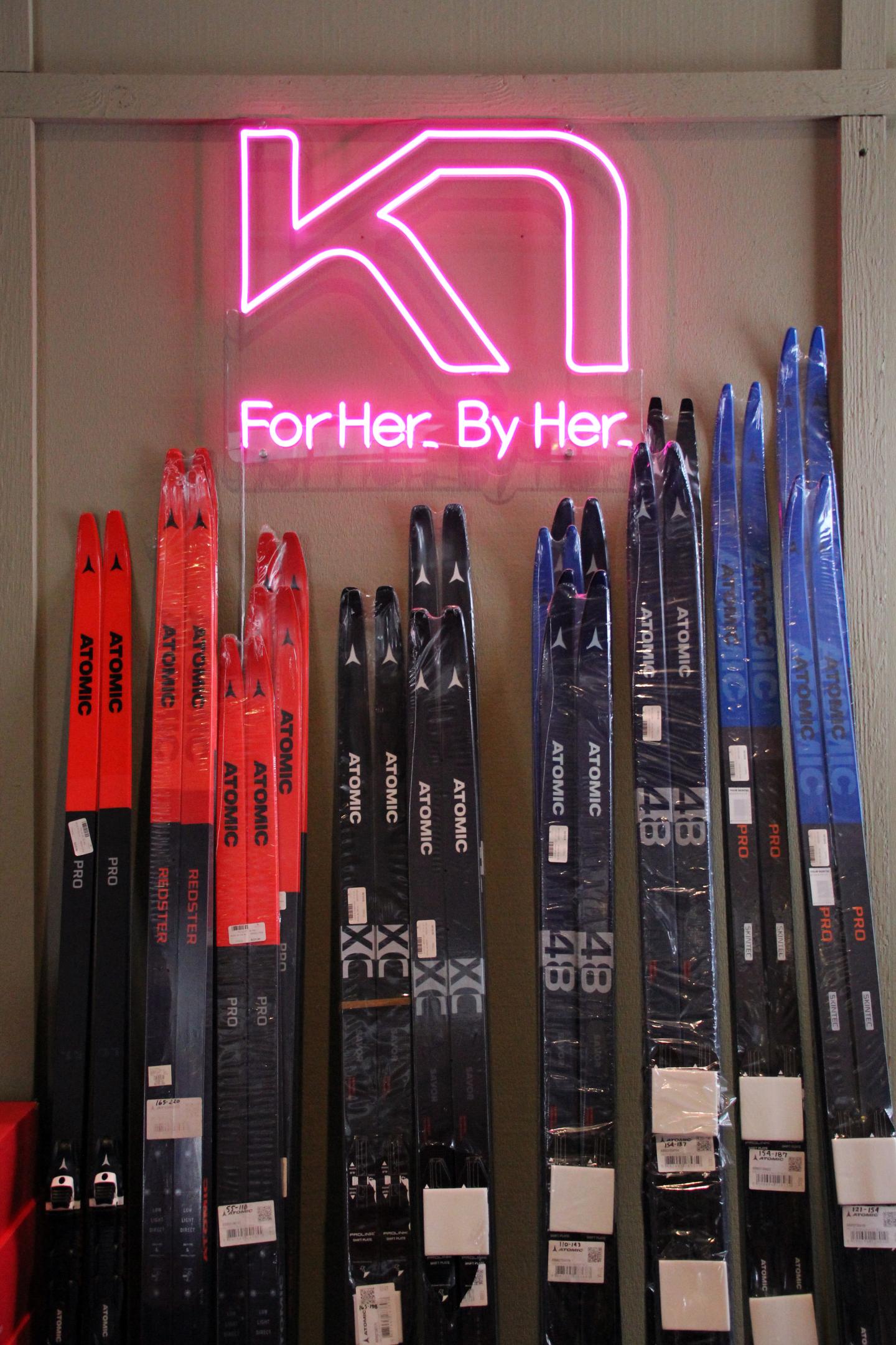 Colorful skis displayed under pink neon sign.