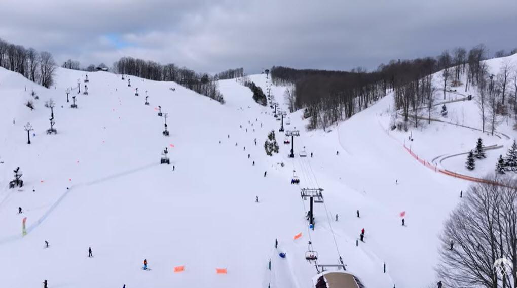 Snow-covered ski slopes with skiers and a blue sky.