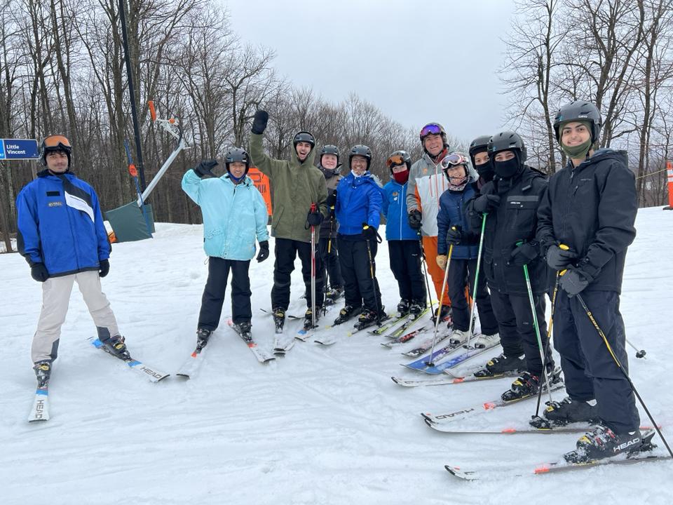 Group of skiers posing on snowy slope, wearing helmets and winter gear.