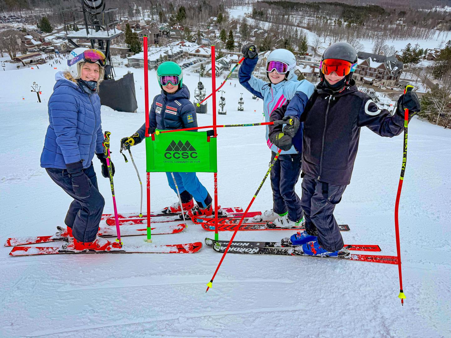 Skiers posing on a snowy hill, wearing winter gear and holding ski poles.