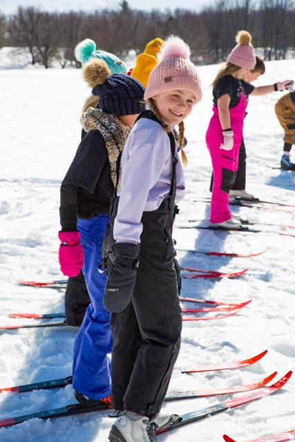 Children skiing in a snowy landscape, wearing colorful winter gear.