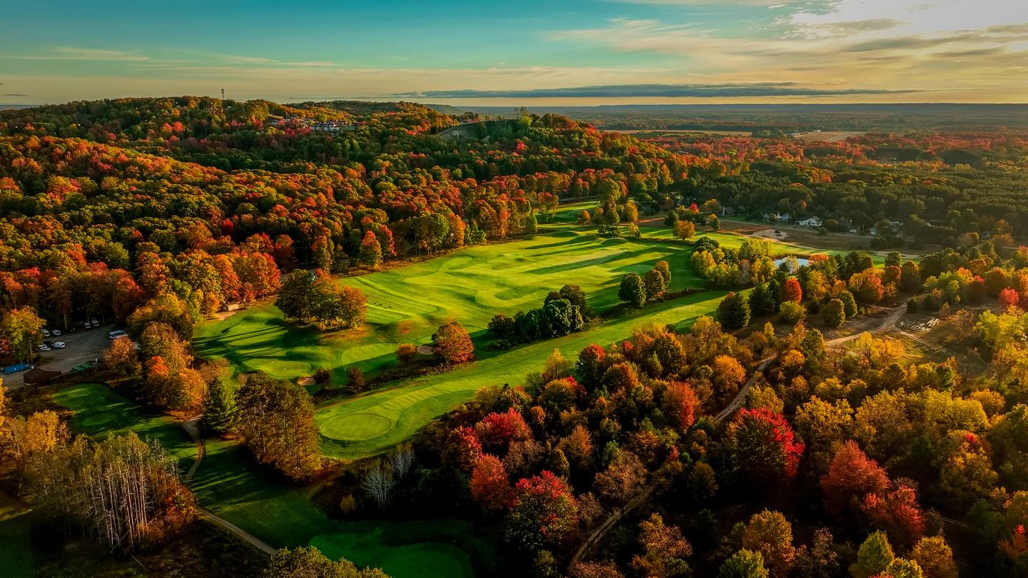 Colorful autumn landscape with the Golf Learning Center surrounded by vibrant fall foliage.
