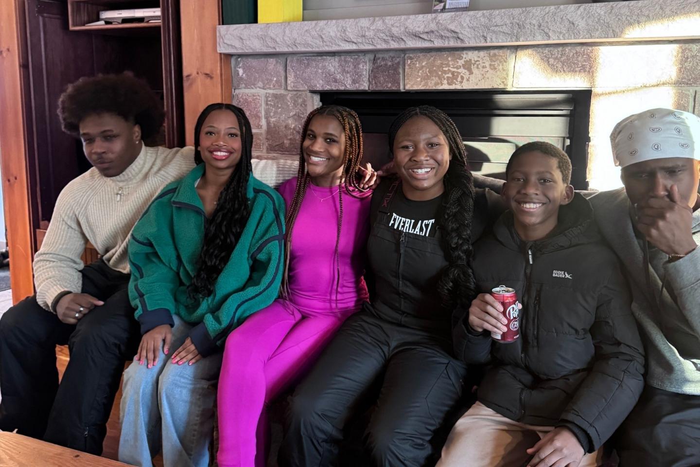 A group of six people smiling on a couch in a cozy room.